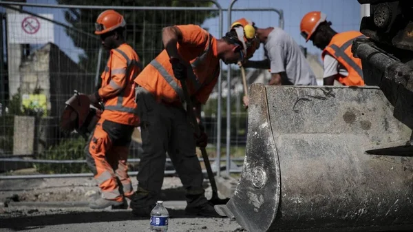 Ouvriers du bâtiment en tenue de sécurité sur un chantier, illustrant les métiers exposés aux canicules.