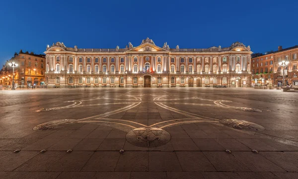 Place du Capitole à Toulouse, au crépuscule, avec sa célèbre croix occitane au sol.