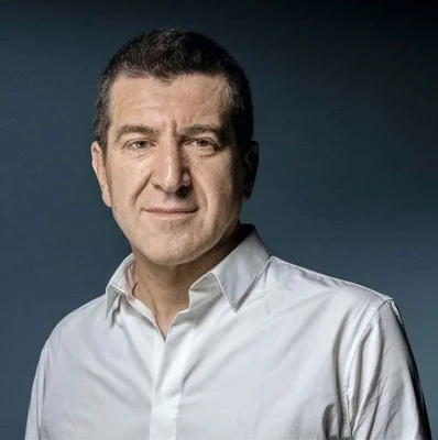 Portrait de Matthieu Pigasse en chemise blanche sur fond bleu.