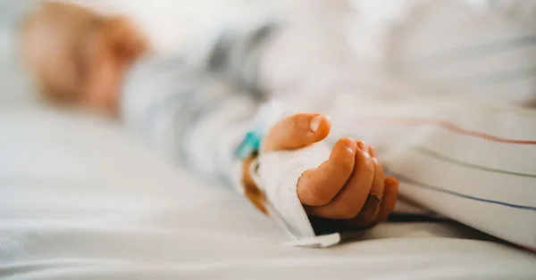 Main d'un patient hospitalisé avec une perfusion intraveineuse, illustrant les soins de fin de vie.