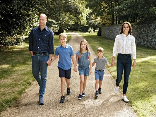 William, Kate et leurs enfants marchant main dans la main sur un chemin de gravier.
