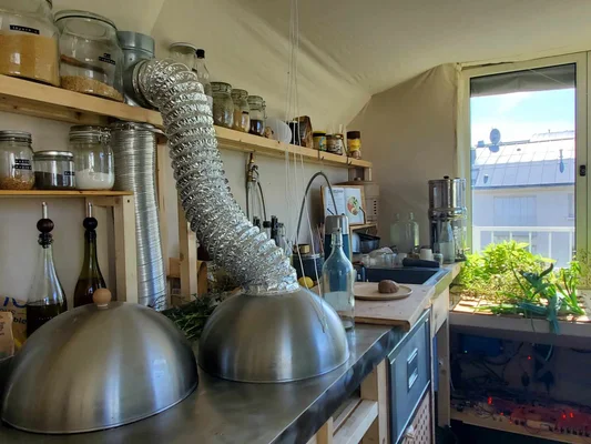 Cuisine low-tech équipée de rangements en bois et d'un système de ventilation.
