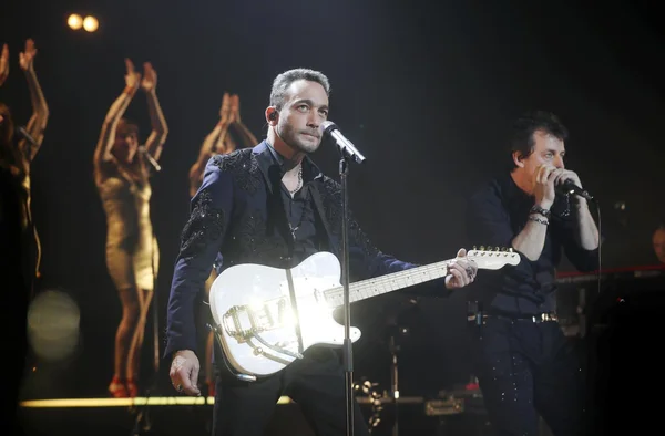 Jean-Baptiste Guégan sur scène, guitare électrique blanche en main, lors d'un concert.