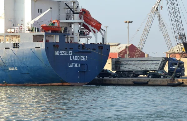 Le cargo 'LAODICEA' amarré dans un port libanais, avec un camion-benne et des voitures.