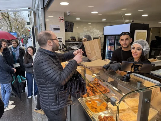 Client au comptoir d'un restaurant Master Poulet, entouré d'employés et d'une file d'attente.