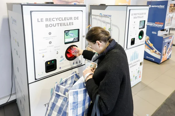 Une utilisatrice insère une bouteille dans un recycleur automatique en magasin.