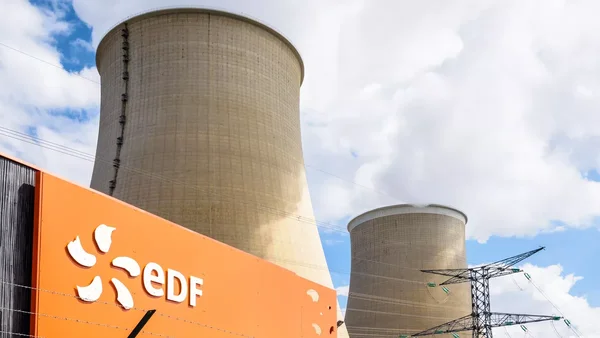 Tours de refroidissement d'une centrale nucléaire avec le logo EDF au premier plan et lignes haute tension.