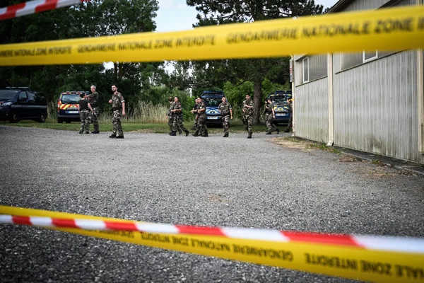 Des gendarmes et véhicules officiels derrière un ruban de sécurité sur le site des recherches.