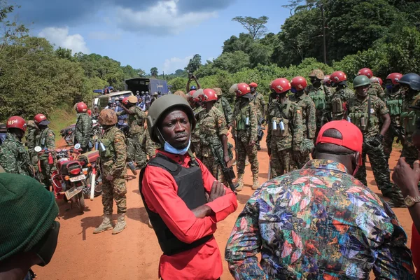 Des soldats ougandais en patrouille dans une zone rurale boisée.