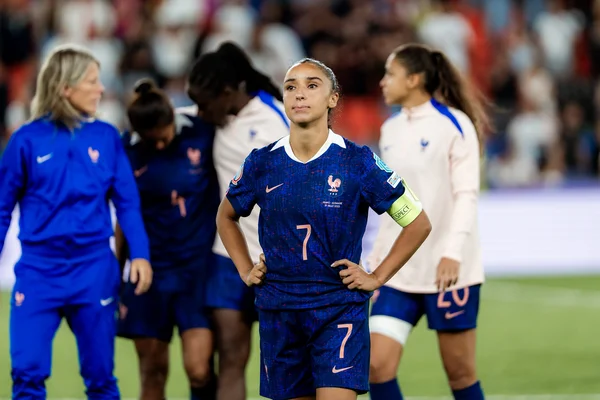 Joueuse des Bleues avec le brassard de capitaine, sur la pelouse, mains sur les hanches.