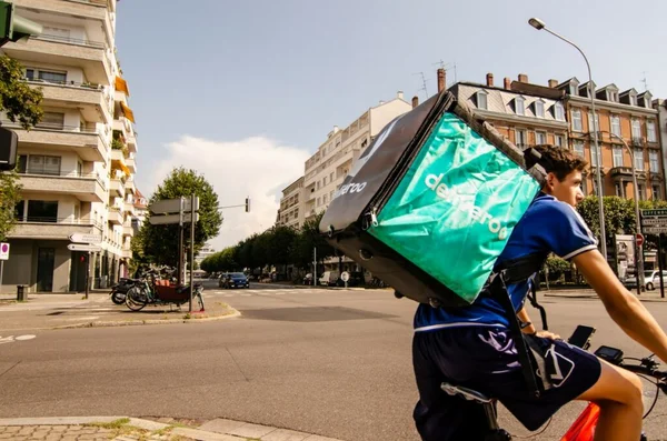 Livreur à vélo des plateformes numériques circulant en ville avec un sac isotherme bleu et noir.