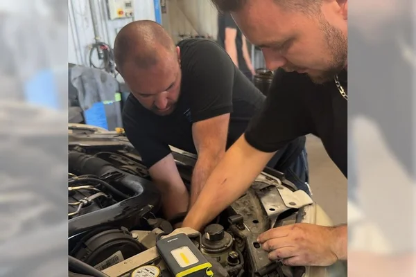 Mécaniciens intervenant sur un moteur de voiture en garage.