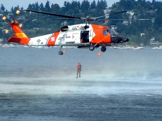 Hélicoptère HH-60 Jayhawk en mission de sauvetage au-dessus d'un plan d'eau.