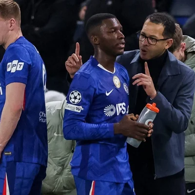 Liam Rosenior en pleine discussion avec un joueur de Chelsea sur le bord du terrain.