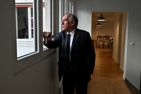 François Bayrou, debout près d'une fenêtre, regarde au loin.