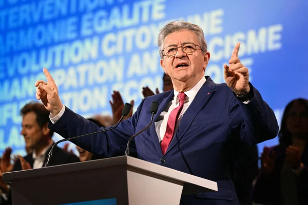 Jean-Luc Mélenchon officialisant sa candidature à un pupitre devant un écran.