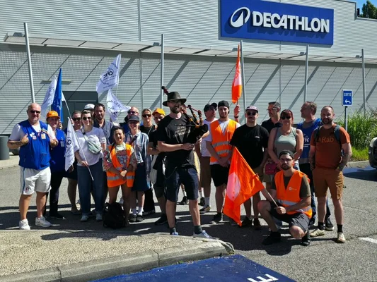 Mobilisation de salariés Decathlon à La Tronche et Échirolles pour des hausses de salaire, avec familles et musique.