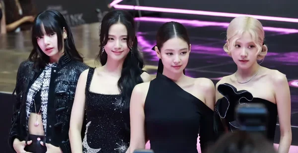 Blackpink en tenue noire posant lors d'un photocall sur fond violet.
