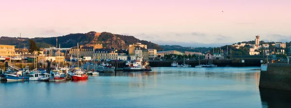 Le port de Cherbourg au crépuscule, avec des bateaux de pêche amarrés, cadre des assises annuelles.