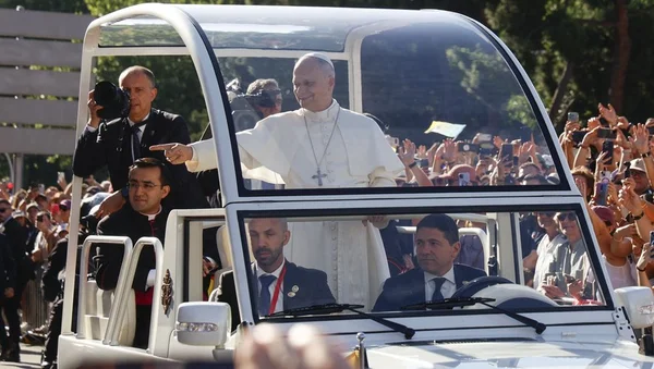 Le pape Léon XIV salue la foule depuis la papamobile, les fidèles immortalisant l'instant avec leur téléphone.