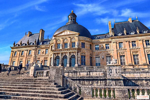 Le château de Vaux-le-Vicomte, vu depuis ses jardins, avec des visiteurs sur le grand escalier.