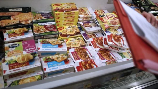 Rayon de surgelés contenant des lasagnes et plats cuisinés, avec un client choisissant un produit.
