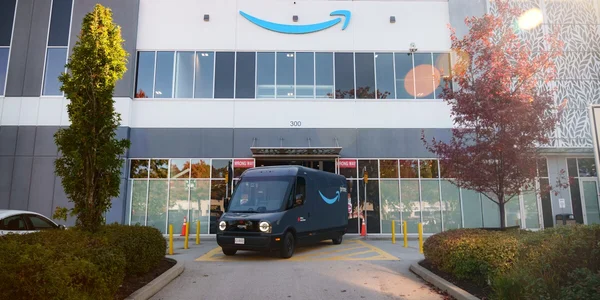 Camionnette de livraison Amazon Prime stationnée devant un immeuble de bureaux moderne au Canada.