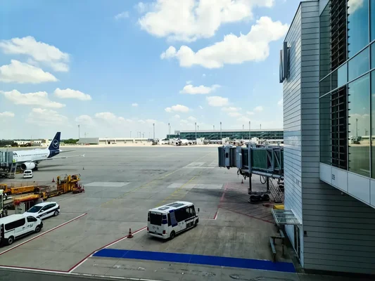 Vue du tarmac de l'aéroport de Munich avec un avion Lufthansa et des véhicules de service au sol.