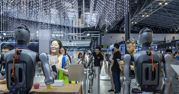 Des robots humanoïdes présentés lors d'une exposition technologique, observés par des visiteurs.