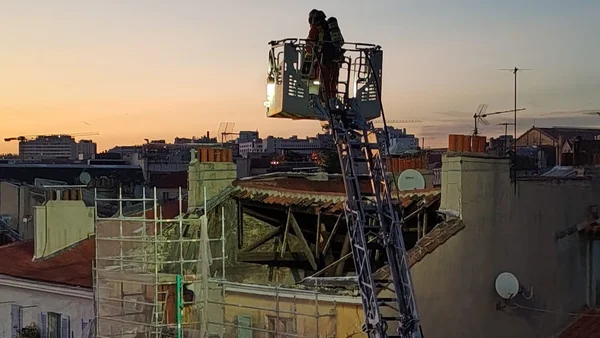Ouvriers en nacelle lors de travaux d'entretien en hauteur à Marseille au crépuscule.