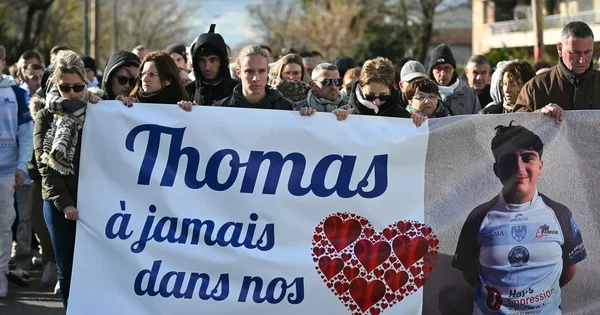 Manifestants lors d'un hommage à Thomas, brandissant une banderole avec sa photo et un message d'affection.