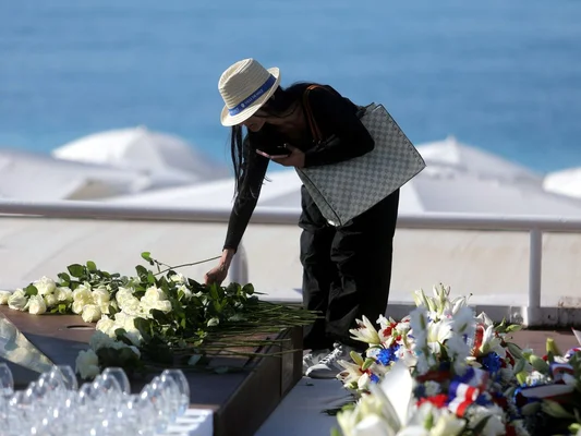 Une femme dépose des roses blanches sur une table commémorative dédiée aux victimes de l'attentat du 14 juillet 2016 à Nice.