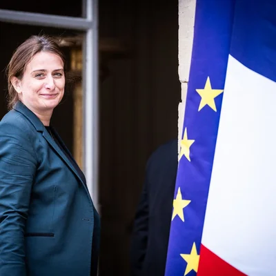 Une élue des Écologistes posant devant les drapeaux français et européen, en soutien à la pétition pour le congé climatique.