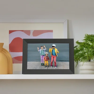 Cadre Aura Ink sur une étagère, affichant une photo de trois enfants devant une porte bleue.
