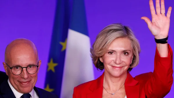 Valérie Pécresse accompagnée de Philippe Bas, lors d'une prise de parole, avec les drapeaux français et européen en toile de fond.