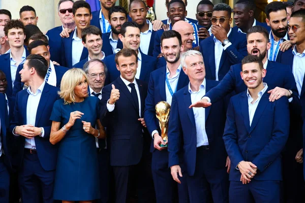 Emmanuel Macron, Brigitte Macron et Didier Deschamps avec les Bleus et le trophée de la Coupe du monde.