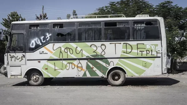 Un bus blanc portant les inscriptions 'TPLF' et des graffitis en amharique, stationné sur une piste après l'accident.