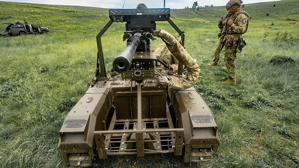 Soldat ukrainien utilisant une station d'arme télécommandée sur un véhicule blindé dans un champ.