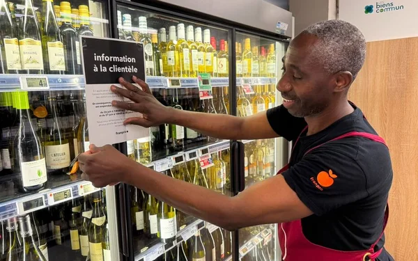 Un employé de magasin installe un panneau informant de l'interdiction de vente d'alcool ce week-end à Paris.
