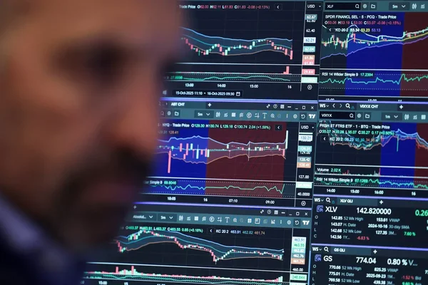 Écrans de trading affichant des graphiques financiers, en arrière-plan d'une personne floue.