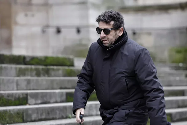 Patrick Bruel à l'extérieur, près de marches en pierre.