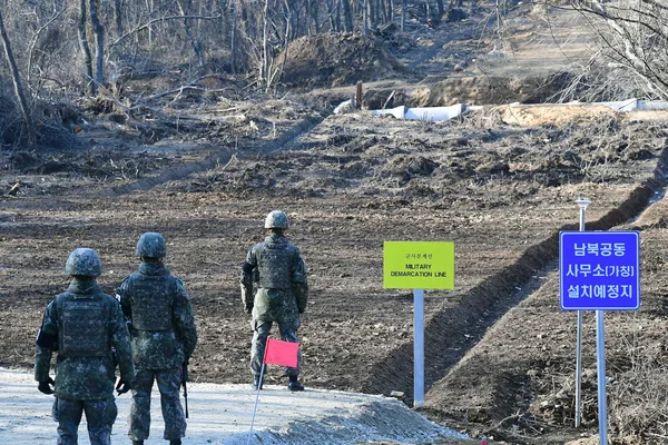 Des soldats nord-coréens tentent de franchir la frontière vers le sud, dans une zone militaire marquée par des excavations et des panneaux de démarcation.
