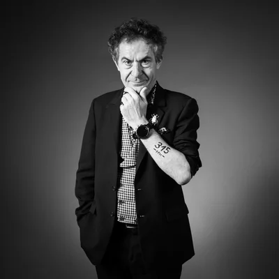 Étienne Klein en portrait noir et blanc, la main au menton, laissant voir un tatouage.