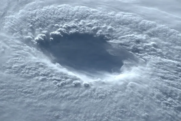Photographie aérienne d'un trou circulaire dans la couche nuageuse, caractéristique d'un œil de cyclone.
