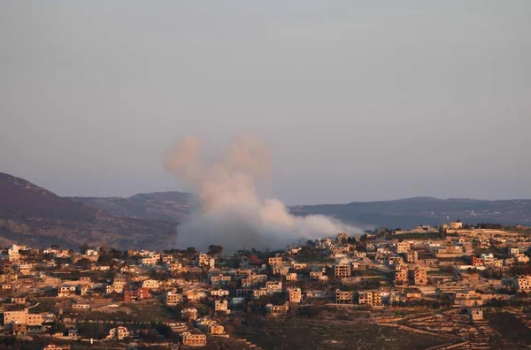 Panache de fumée s'élevant au-dessus d'une ville collinaire au Liban.