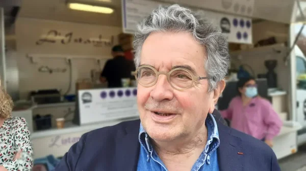 Alain Claeys, en blazer bleu et chemise en jean, pose devant un food truck à Poitiers.