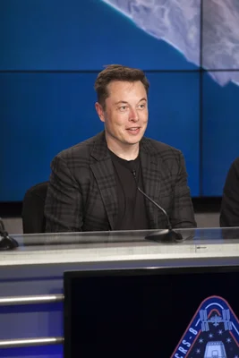 Elon Musk lors de la conférence de presse post-lancement de la mission SpaceX CRS-8, avec une vue de la Terre en arrière-plan.