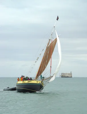 Le fort Boyard vu depuis un voilier naviguant à proximité, sous un ciel couvert.