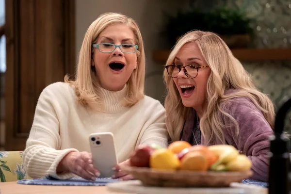 Deux personnages de la série Leanne réagissant à une nouvelle choc sur leur téléphone.
