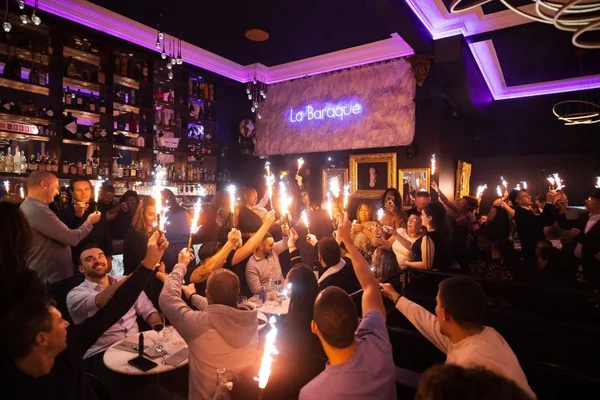 Soirée animée à La Baraque : des invités célèbrent avec des cierges magiques dans une ambiance festive.
